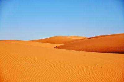 Sand dunes in desert against clear sky