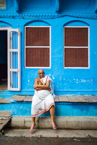 Portrait of man sitting outside house