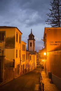 Street amidst buildings against sky at dusk