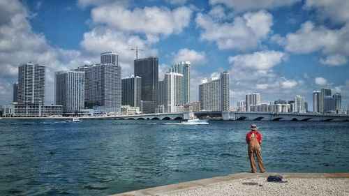 Man standing on beach with city in background