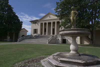 Statue by historic building against sky