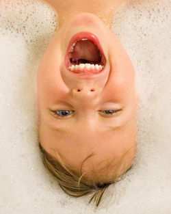 Up close of boy laughing in bathtub with bubbles