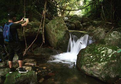 Man photographing waterfall in forest