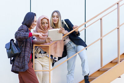 Women sharing tablet pc on staircase