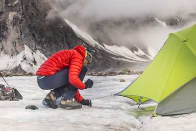 Mountaineer staking tent on glacier in akshayak pass.