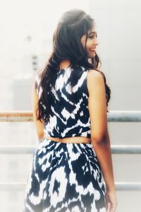 Young woman looking away while standing against white background