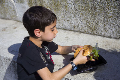 High angle view of eating burger by wall