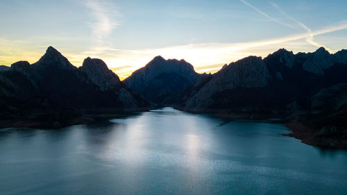 Scenic view of lake and mountains against sky during sunset