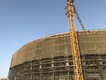 Low angle view of crane against clear blue sky