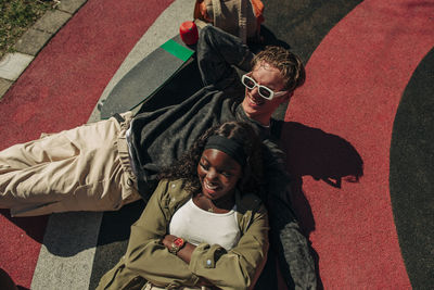 Multiracial young man and woman lying in playground on sunny day