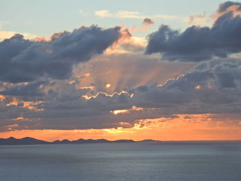 Scenic view of sea against dramatic sky during sunset