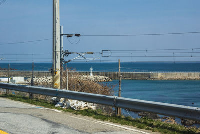 Road by sea against clear blue sky