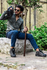 Full length portrait of young man sitting outdoors