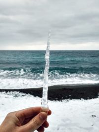 Cropped hand of person holding snow at beach