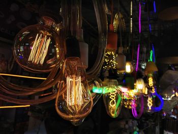 Close-up of illuminated light bulbs hanging at night