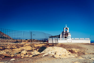 Built structure on rocks against clear blue sky