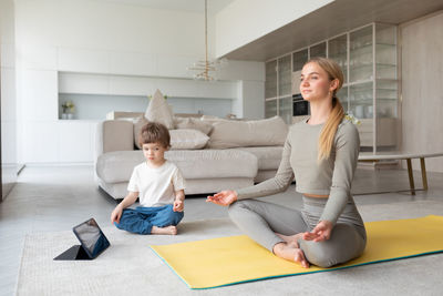 Young woman using phone while sitting on sofa at home