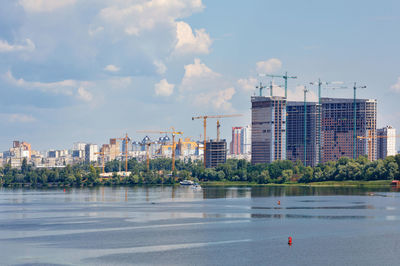 The construction of modern residential buildings rises above the wide surface of the river.