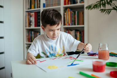 Boy doing painting while sitting at home