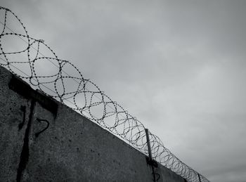 Low angle view of barbed wire against sky