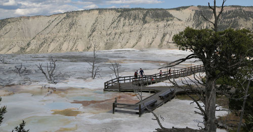 People on bridge at yellowstone national park against mountain