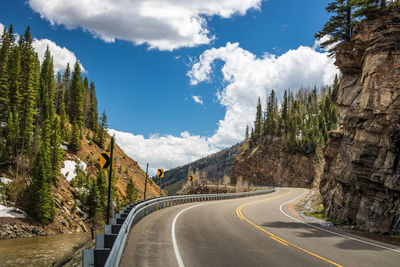 Panoramic view of road amidst trees against sky