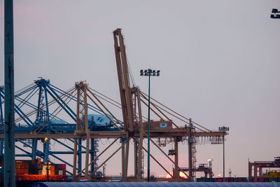 Cranes at commercial dock against clear sky