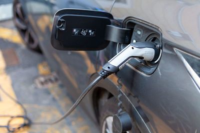 A cable is recharging an electric car at the charging station