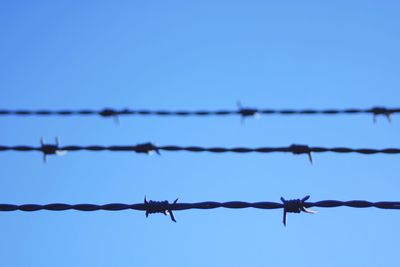 Low angle view of barbed wire against clear sky