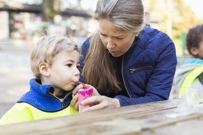 Teacher feeding drink from juice box at table