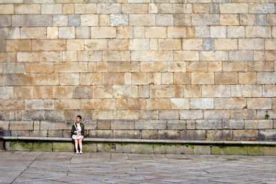Full length of woman standing against brick wall