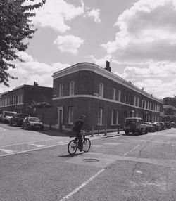 Person riding bicycle down apartment lined street