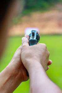 Close-up of hand aiming gun at target 