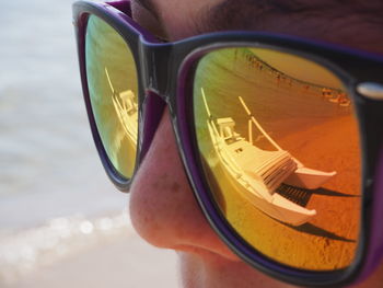 Boat reflecting on woman sunglass at beach