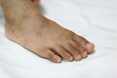 Close-up of human hand on bed