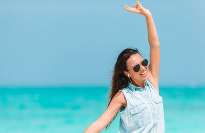 Portrait of woman in sunglasses at beach against sky