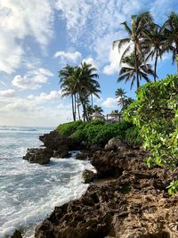 Scenic view of trees growing by sea against sky