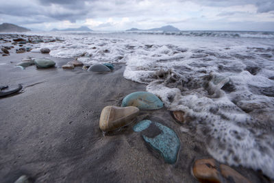 Close-up of rocks on beach against sky