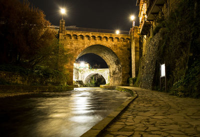 Arch bridge over illuminated street at night