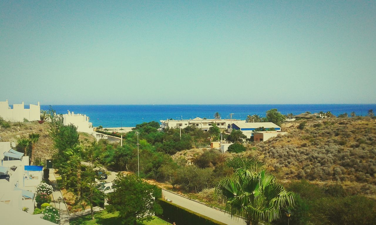 horizon over water, sea, clear sky, copy space, water, blue, built structure, building exterior, architecture, tranquil scene, beach, scenics, tree, nature, beauty in nature, plant, tranquility, high angle view, house, day