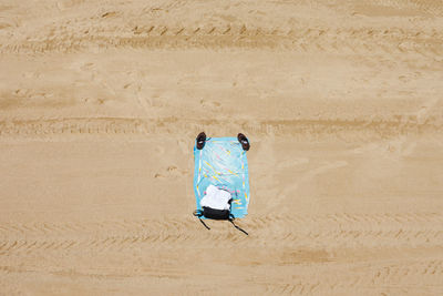 Directly above shot of shoes and towel on sand at beach