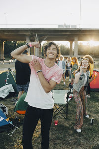 Portrait of smiling man flexing muscles while enjoying with friends in music festival