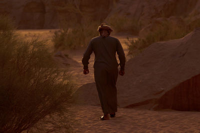 Rear view of man walking on sand