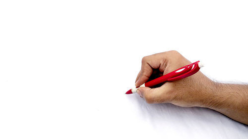 Close-up of hand holding red over white background