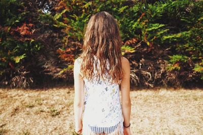 Young woman standing against tree