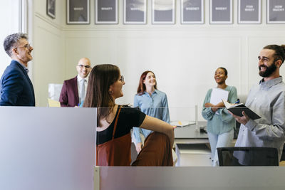 Smiling male and female entrepreneurs discussing strategies at workplace