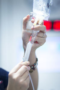 Cropped hands of doctor injecting syringe in iv drip at hospital