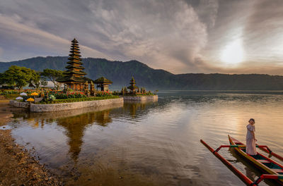 Traditional building by lake against sky