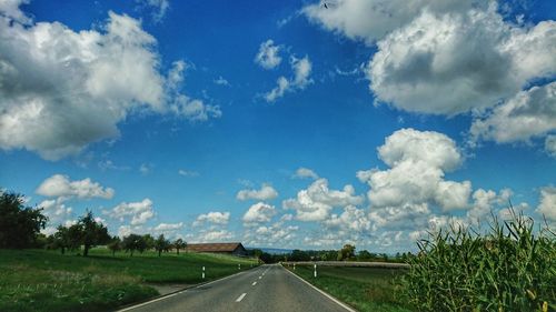 Road amidst field against sky
