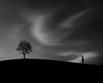 Low angle view of silhouette person standing on field against sky